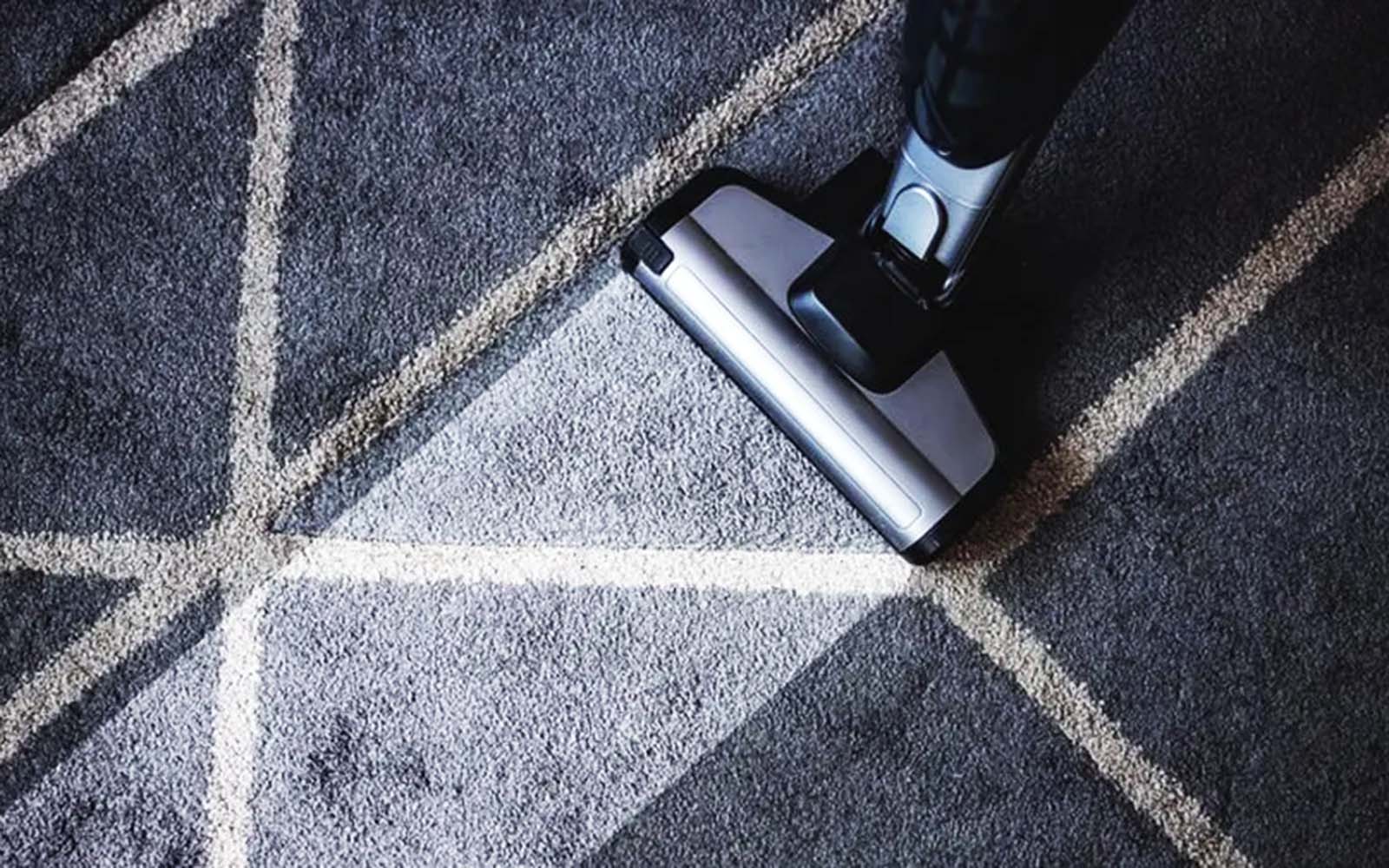 A person using a carpet cleaning machine on a living room carpet