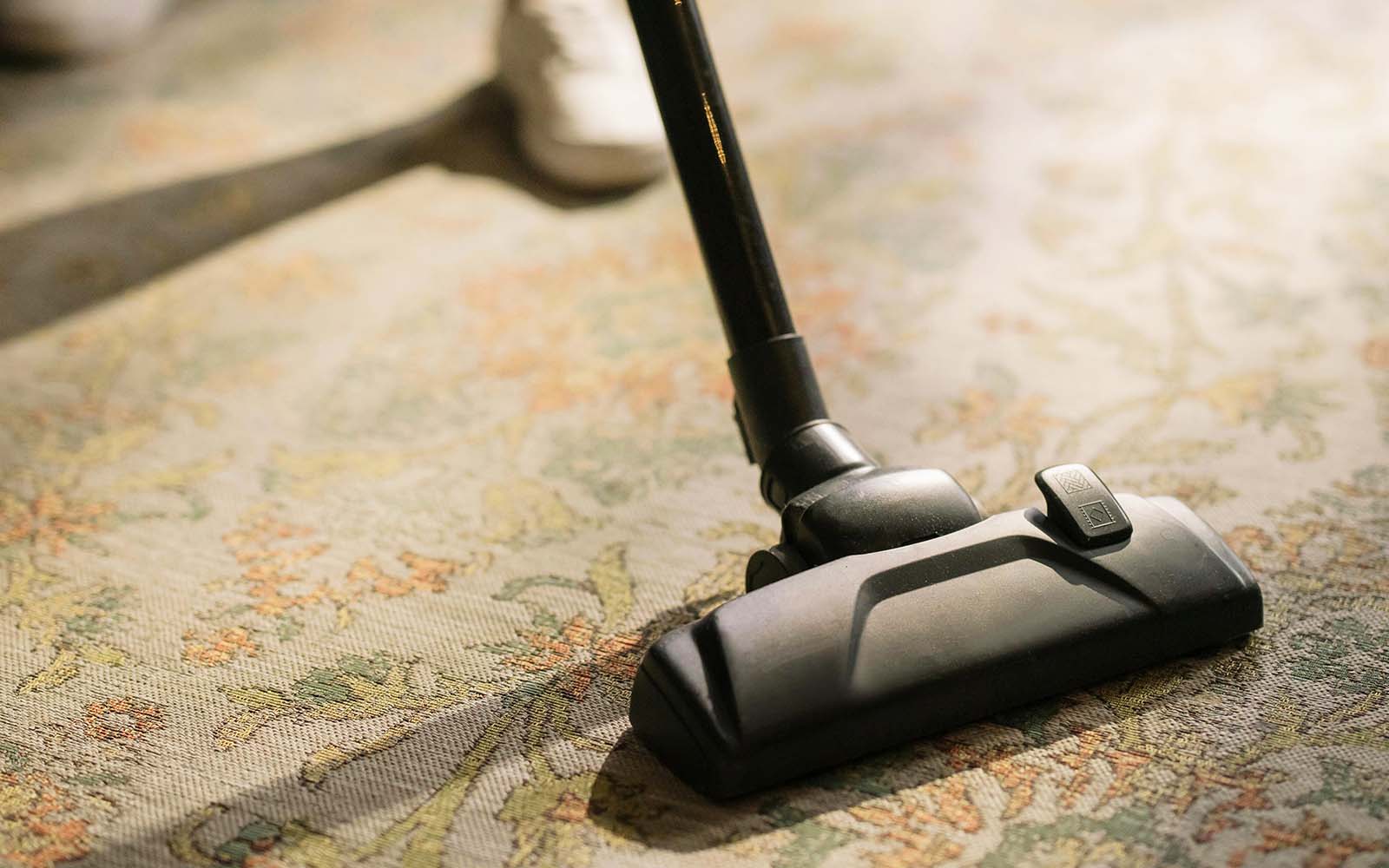 A person vacuuming a carpet with a professional vacuum cleaner Carpet Cleaning Mastery: Vacuum Like a Pro