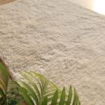 A Plush White Shaggy Rug with a dense, soft texture and pile height placed on a light wooden floor.