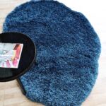 A vibrant blue Organic Shape Shaggy Rug with a plush texture and fluid silhouette styled with a modern black side table.