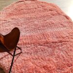 Large pink irregular shaggy rug with an organic wavy shape and plush pile on a wooden floor.
