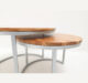 Angled side view of nesting coffee table set with wooden tops and sleek metal frames