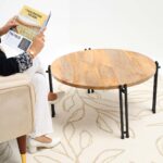 Home décor centerpiece table with a natural round solid wood top and modern black iron legs, perfect for adding rustic warmth to a lounge area.