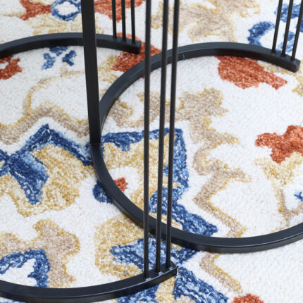 Close-up of black iron base of wooden nesting side tables showing sleek metal frame and sturdy design