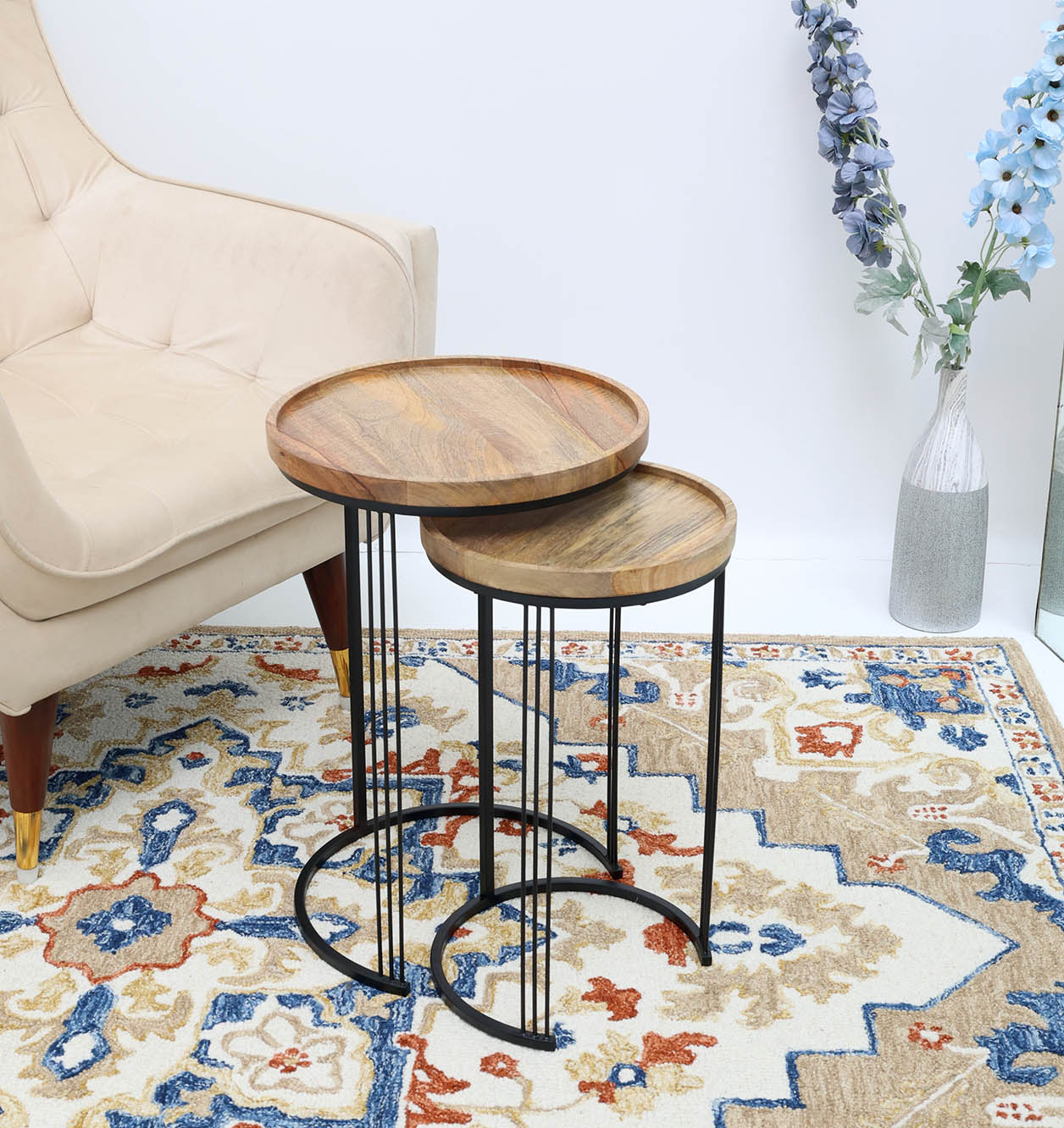 Wooden Nesting Side Tables in Front of Couch – Round Solid Wood Tops with Black Iron Bases Set of 2 wooden nesting side tables with round solid wood tops and black iron bases placed in front of a couch