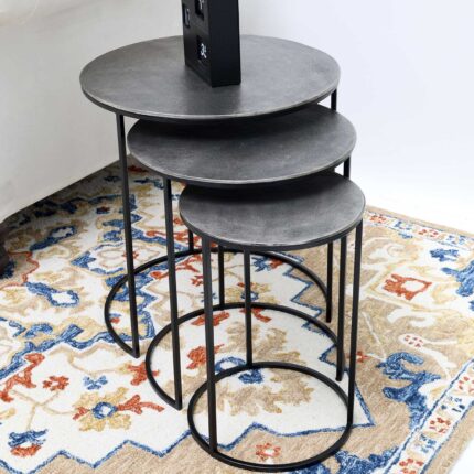 Set of 3 modern nesting side tables with antique brass tops and black iron bases, styled with a black clock on top