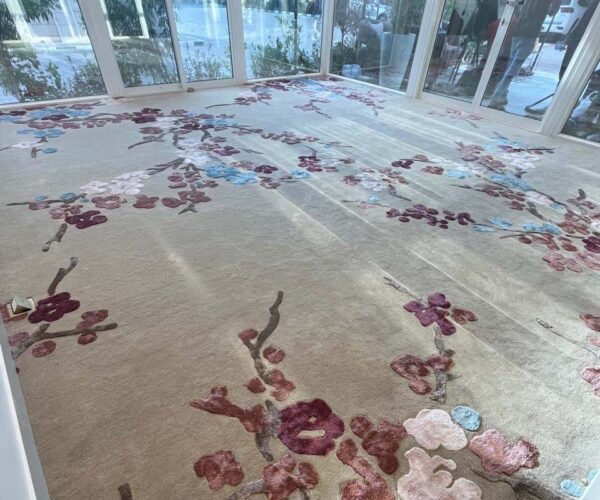 Floral-patterned rug in a bright sunlit room with large windows and modern décor