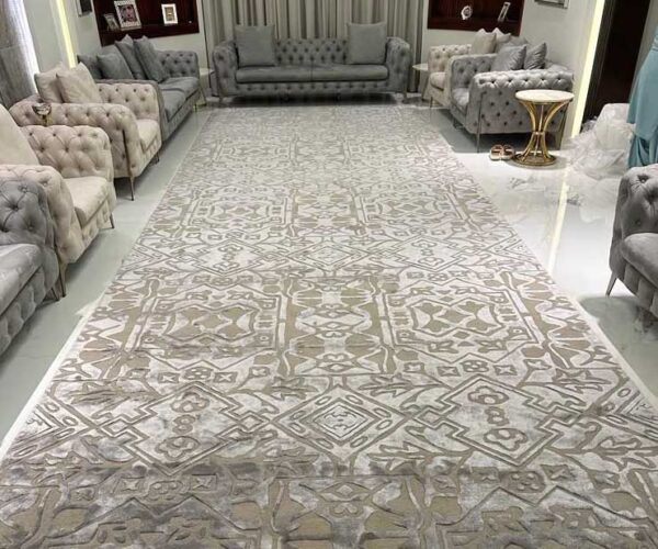 Abstract camouflage pattern rug in shades of brown, beige, taupe, and green, grounding a large white sectional sofa in a bright, modern living room.