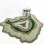 An Organic Green Shaped Rug featuring layered concentric circles in forest green, sage, and cream with a textured hand-carved border.