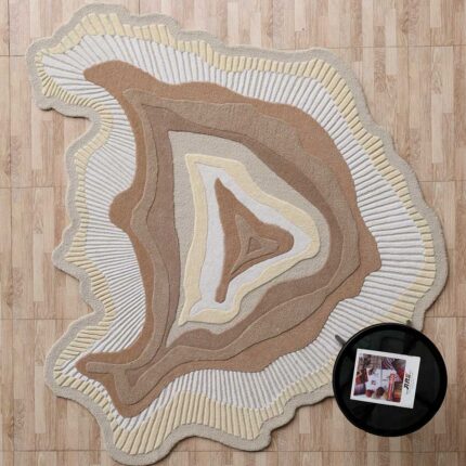 A Sculptural Earth Tone Rug with organic concentric layers in beige and cream, featuring hand-carved textured ridges on a wooden floor.