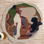 An Earth Tone Abstract Shaped Rug with a fluid organic pattern in green, terracotta, and charcoal on a light wood floor.