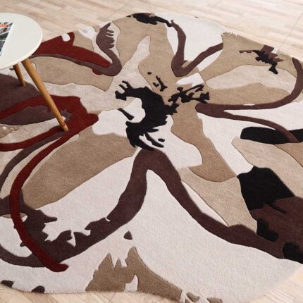 A Floral Artistic Shaped Rug with a large-scale hand-carved flower pattern in burgundy, brown, and cream tones.