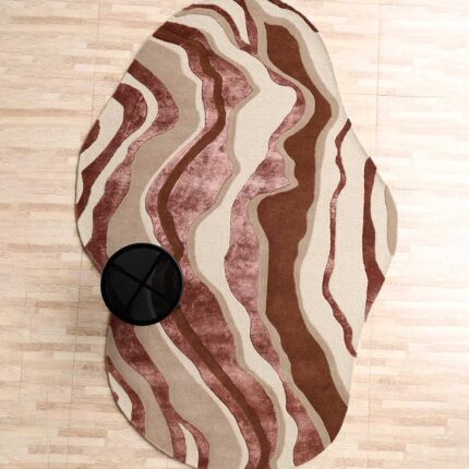 A Wool Shaped Rug with an irregular organic silhouette featuring rhythmic wavy patterns in brown, beige, and rose.