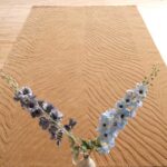 A large Beige Rectangle Rug featuring a hand-carved rhythmic stripe pattern on a light wooden floor.