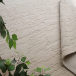 A large Neutral Textured Rug in beige featuring a subtle, organic hand-carved high-low textural pattern across the surface.