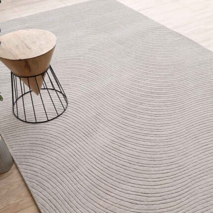 A premium selection of hand tufted carpets featuring a light grey rectangle rug with a deep, hand-carved wavy pattern.