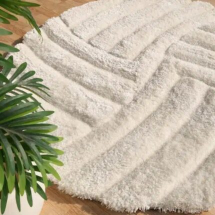 Round white shaggy rug with a carved geometric line pattern and plush pile on a wooden floor.