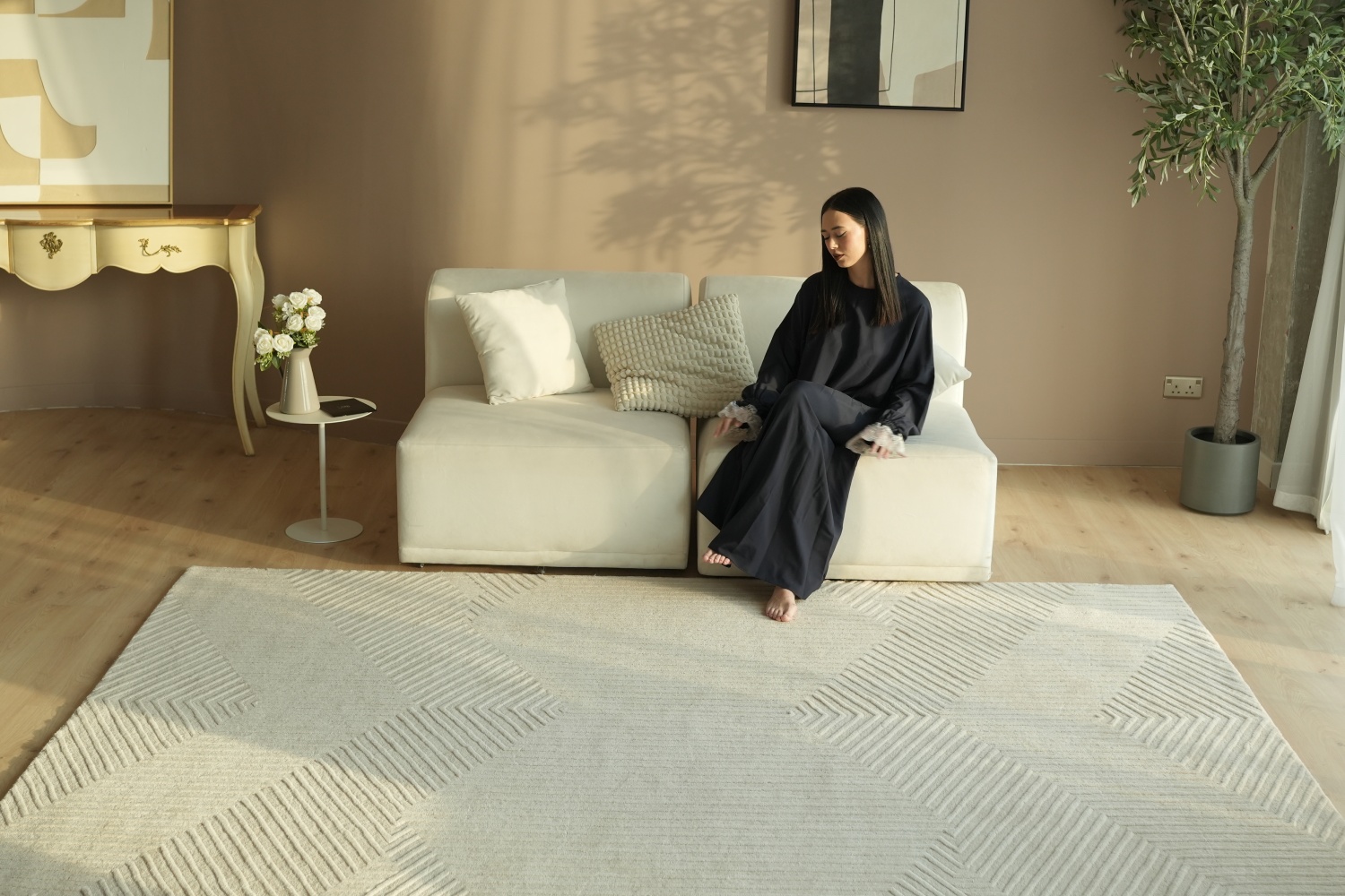 A spacious modern living room featuring a large grey rectangular rugs anchoring a sectional sofa and coffee table.